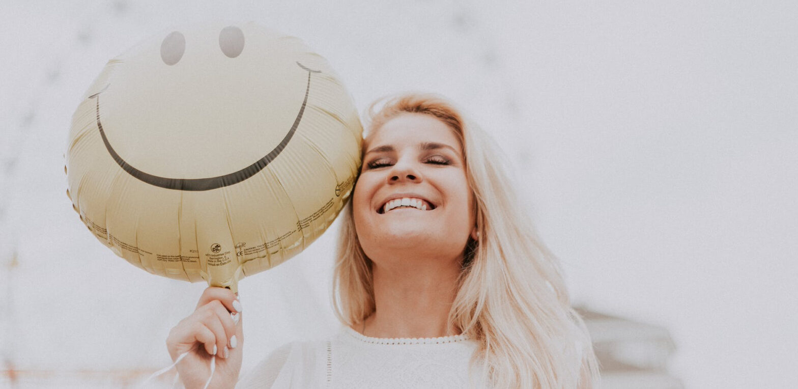 woman holding a smiley balloon